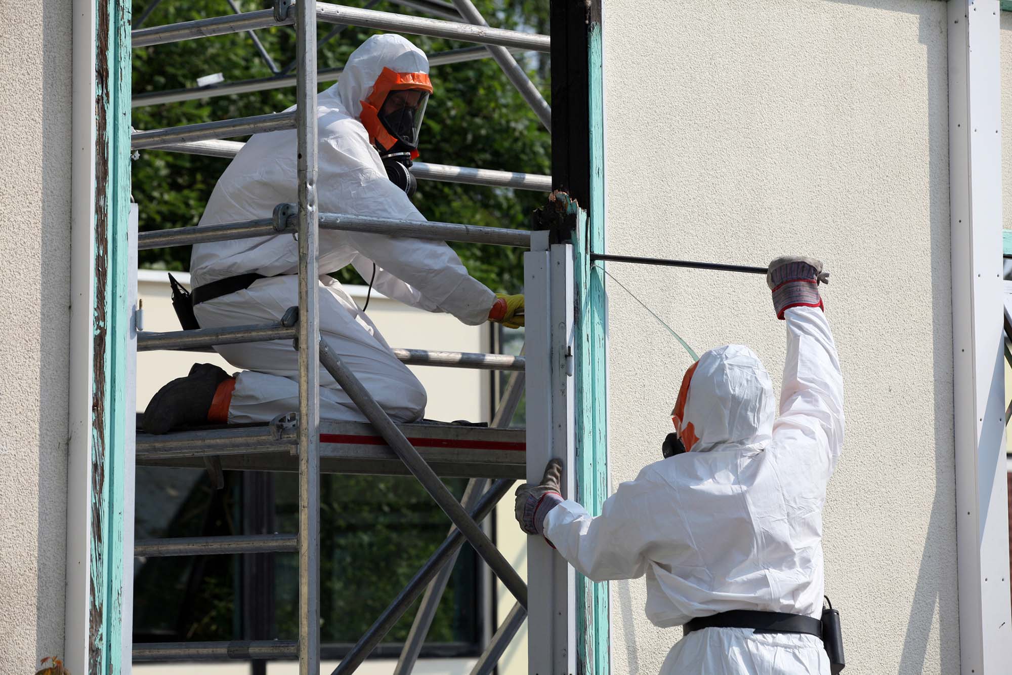 2 workers perform asbestos removal of a building